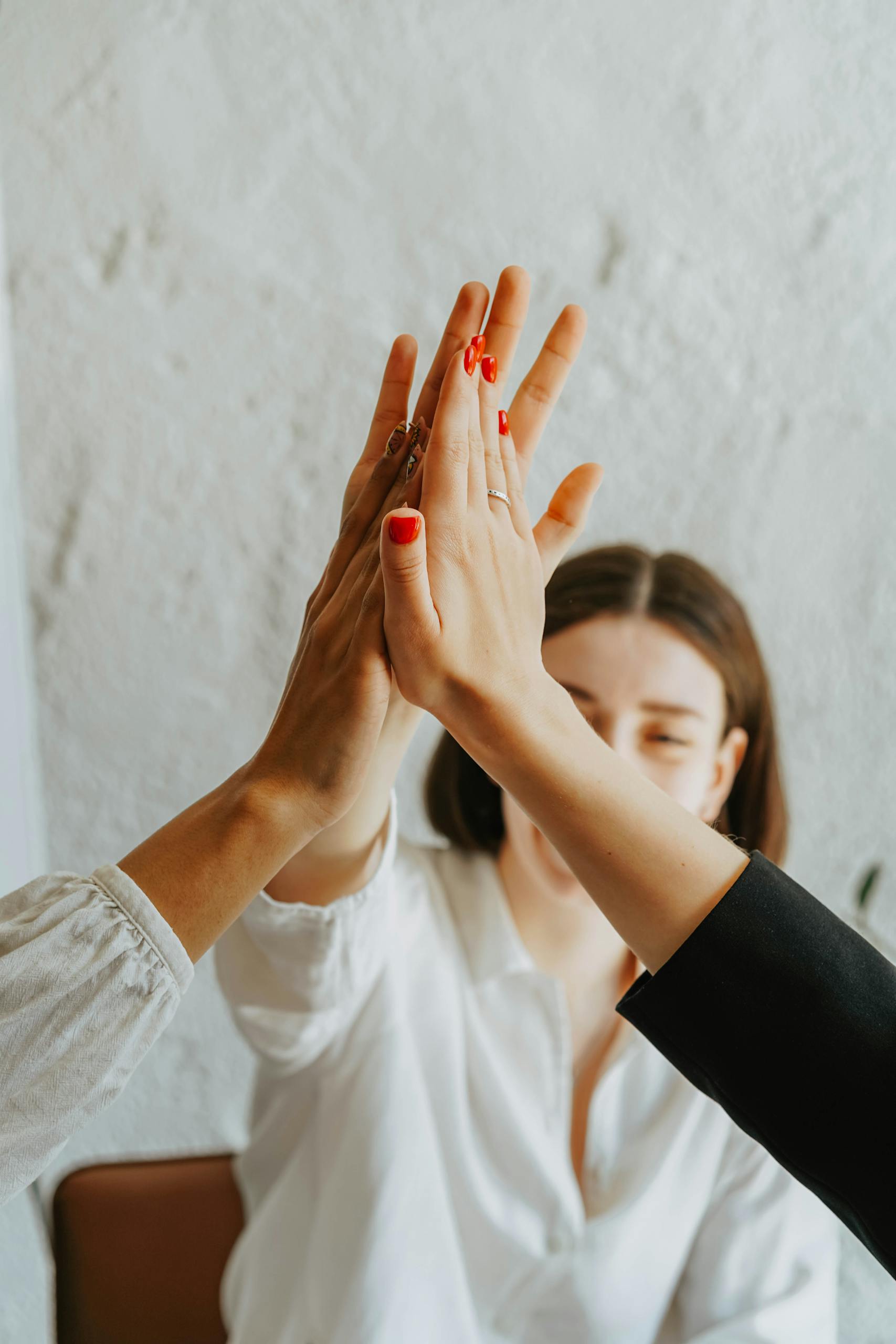 A group of adults in a warm atmosphere celebrating teamwork with a high-five gesture.