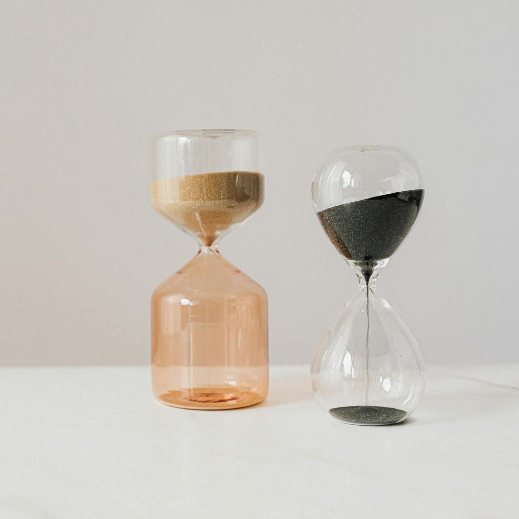 Close-up of two hourglasses on a marble surface, showcasing the passage of time.